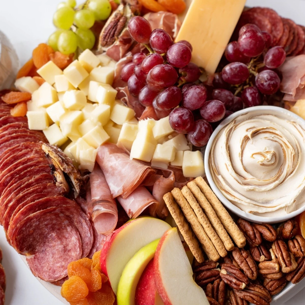 Colorful selection of meats, cheeses, and gingerbread dip on a party platter.