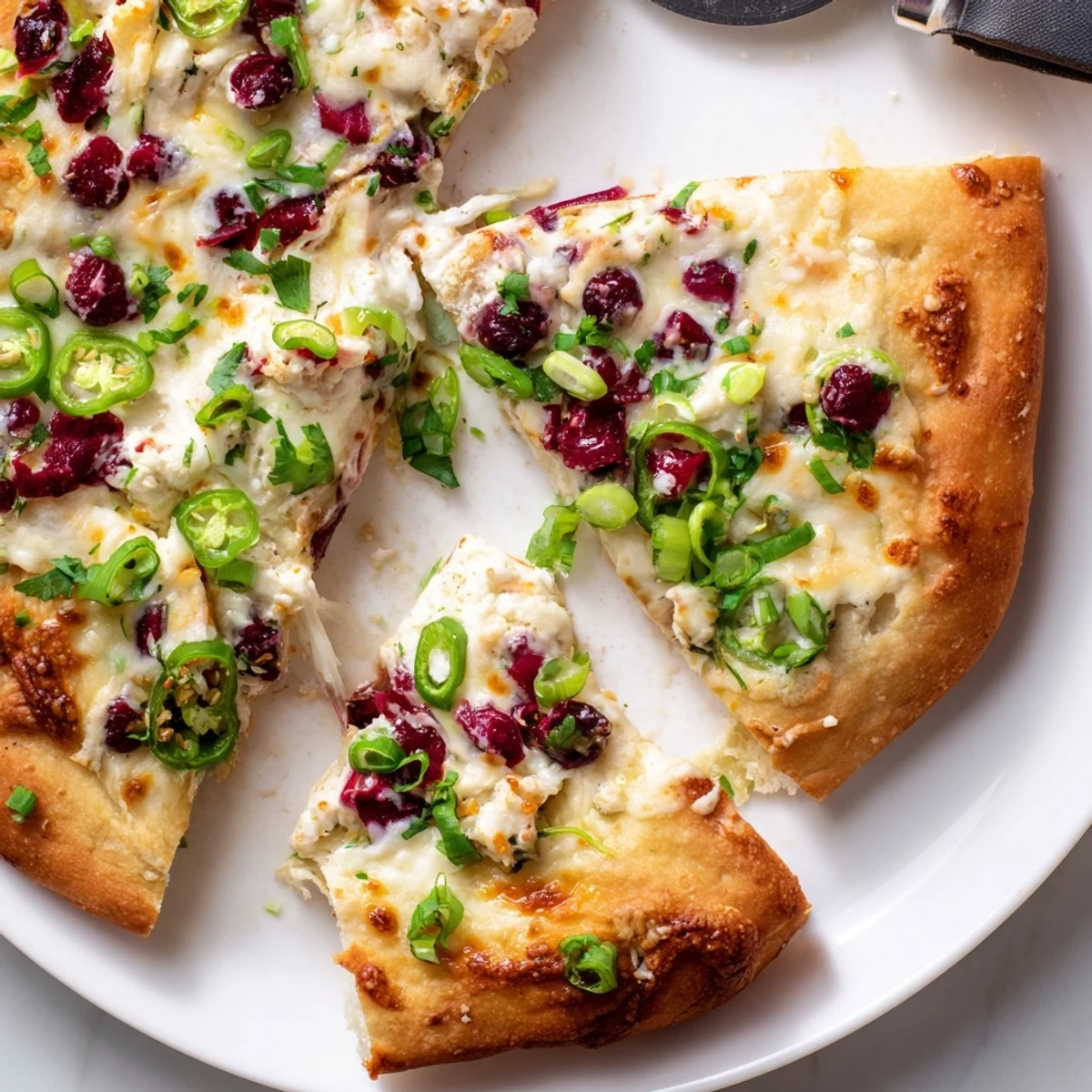 Creamy cranberry jalapeño dip pizza topped with gooey melted cheese and fresh herbs.  