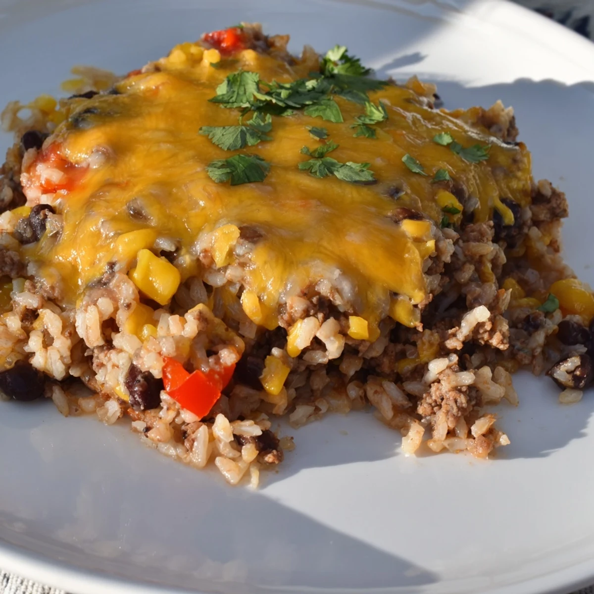 Steaming Tex-Mex Beef & Rice Casserole, bubbling with melted cheddar cheese and hearty ground beef within.