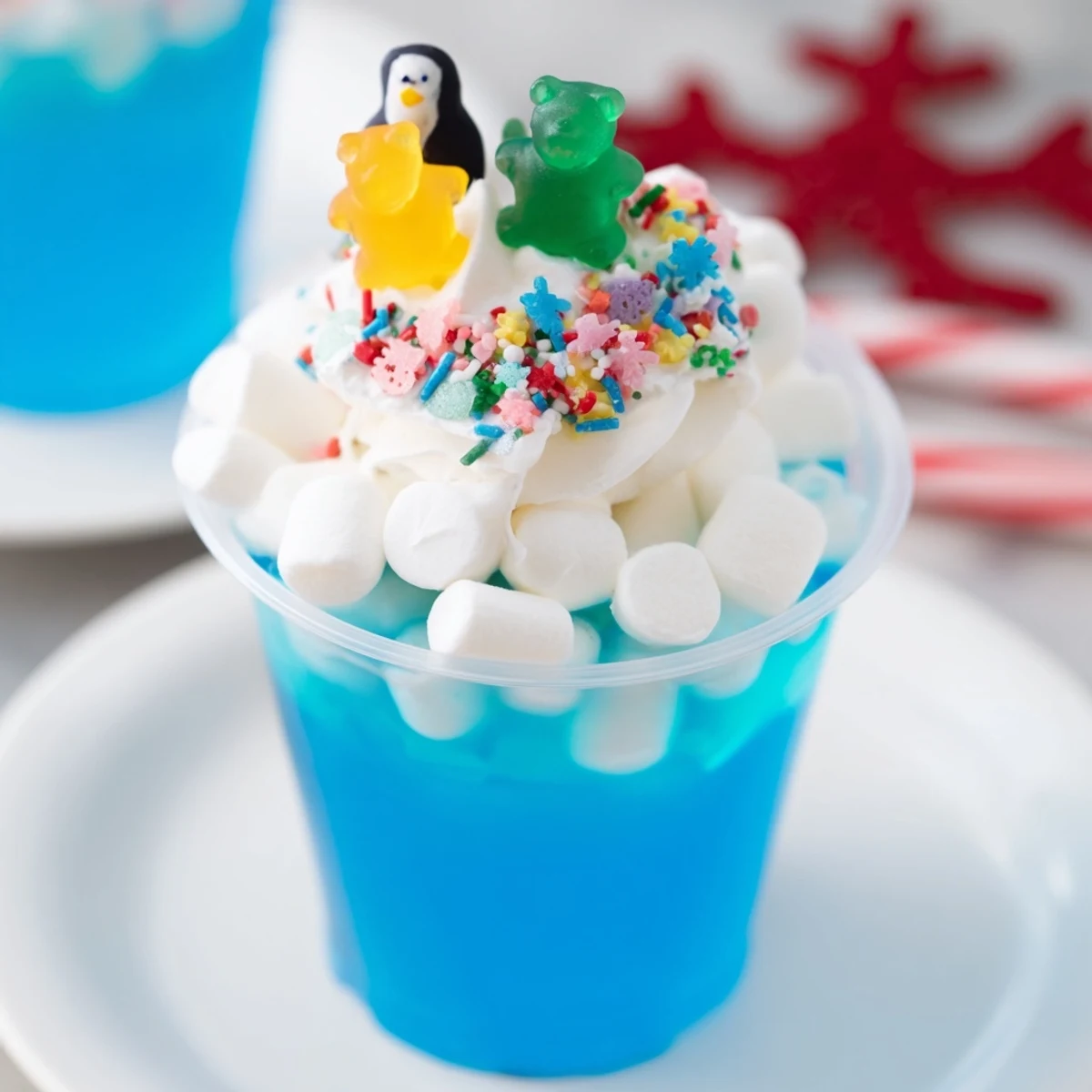 Vibrant snow globe Jello cups, a colorful dessert with blue gelatin and playful marshmallow snow.
