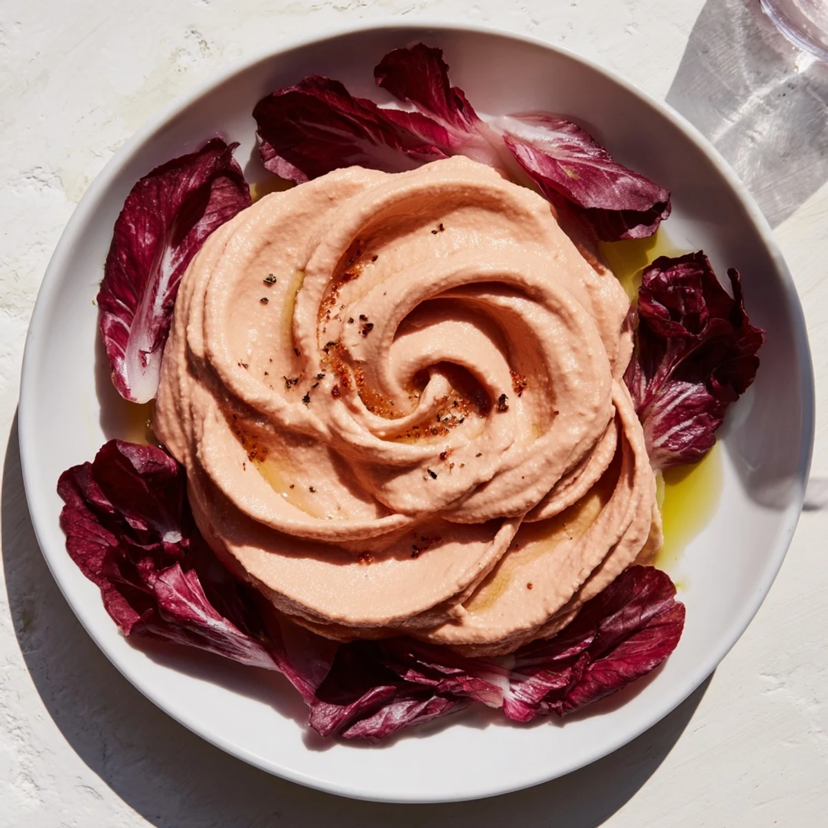 Close-up of The Velvet Rose showing swirls of red beet hummus and a crispy radicchio garnish on a plate.