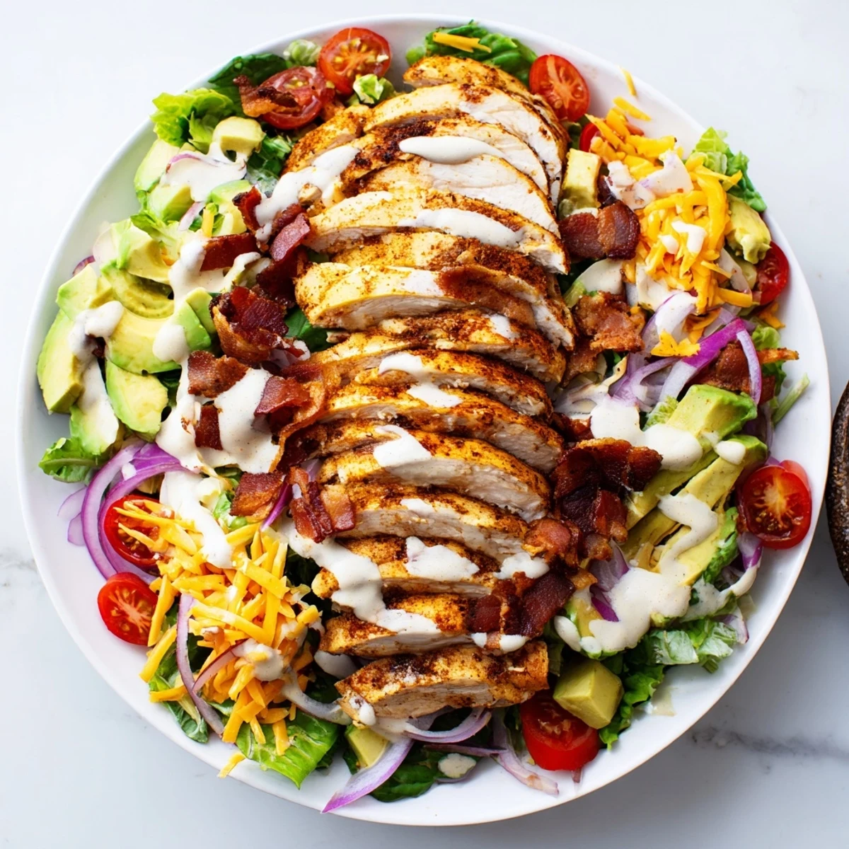 Close-up view of a delicious Crispy Bacon Chicken Salad with juicy grilled chicken and fresh avocado.
