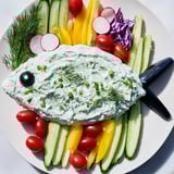The appetizing Ocean Blue Fish-Shaped Dip Tray presents fresh veggies surrounding cool, herbed and blue ranch dips.