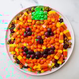 A festive arrangement of a Jack-o-Lantern candy board, featuring bright orange and black sweets.