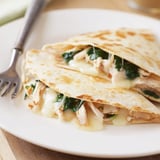 Sizzling flour tortilla filled with juicy chicken, wilted spinach, and gooey mozzarella cheese on skillet.