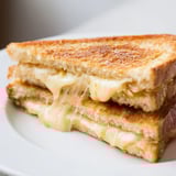 A close-up of the Triple Cheese Sourdough Grilled Cheese, with gooey cheese stretching between buttery, golden-brown sourdough slices.