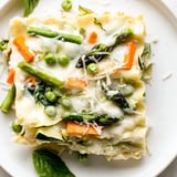 Golden-brown Spring Veggie Alfredo Lasagna bubbling from the oven, garnished with fresh basil and Parmesan.