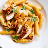 A close-up of creamy Honey Chipotle Chicken Pasta showing tender chicken and al dente penne tossed in a smoky-sweet sauce, with lime wedges nearby.