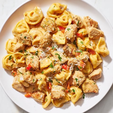Sizzling Zesty Cajun Garlic Parmesan Chicken Tortellini, creamy sauce coats pasta and chicken topped with fresh parsley.