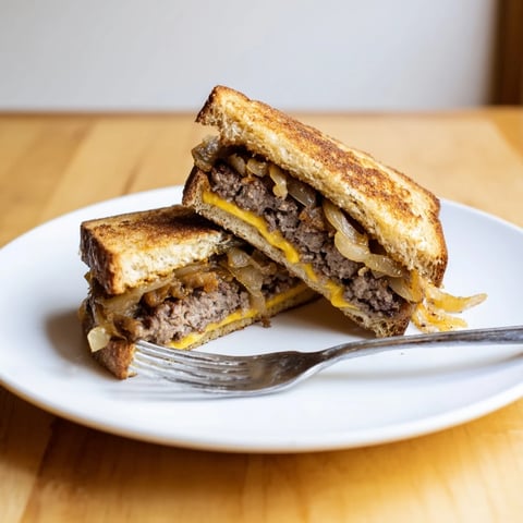 Golden, crispy Patty Melt Skillet with melted Swiss cheese, savory beef patties, and caramelized onions.