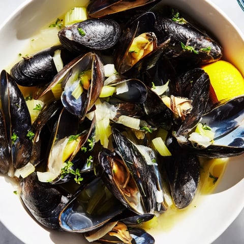 Steaming Belgian Moules Marinière, plump mussels with garlic, herbs, and white wine in a pot.