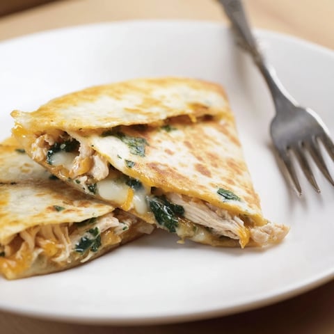 Golden-brown Chicken and Spinach Quesadilla wedges oozing melted mozzarella, served with sour cream and salsa.
