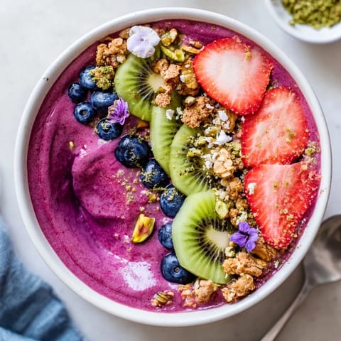 A colorful breakfast bowl featuring creamy purple yam, pistachio, and luscious berries.  