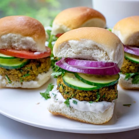 A close-up of delicious baked falafel sliders, with a creamy tahini drizzle visible.