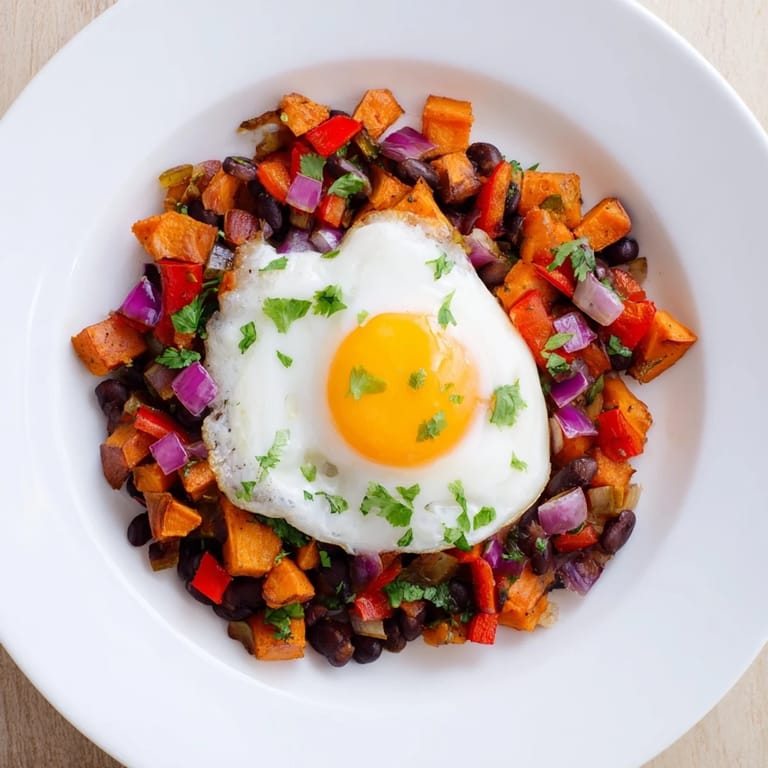 Golden-brown Sweet Potato & Black Bean Breakfast Hash with fresh cilantro and a runny egg yolk.
