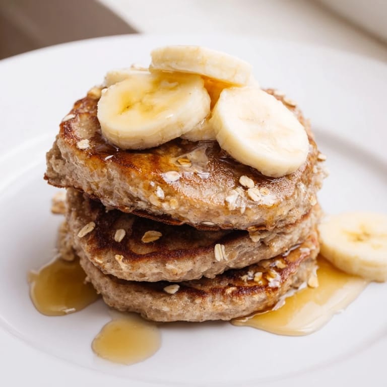 Warm, fluffy banana oat pancakes; a stack of deliciousness, ready to be enjoyed with fresh berries.
