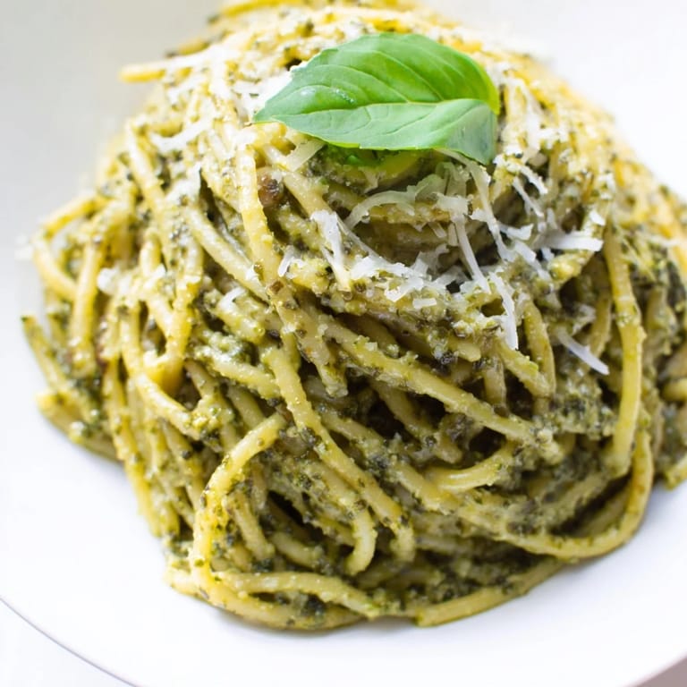 Ready in just thirty minutes, this budget-friendly creamy sunflower seed pesto pasta is served steaming in a white bowl, perfect for a quick and easy dinner.