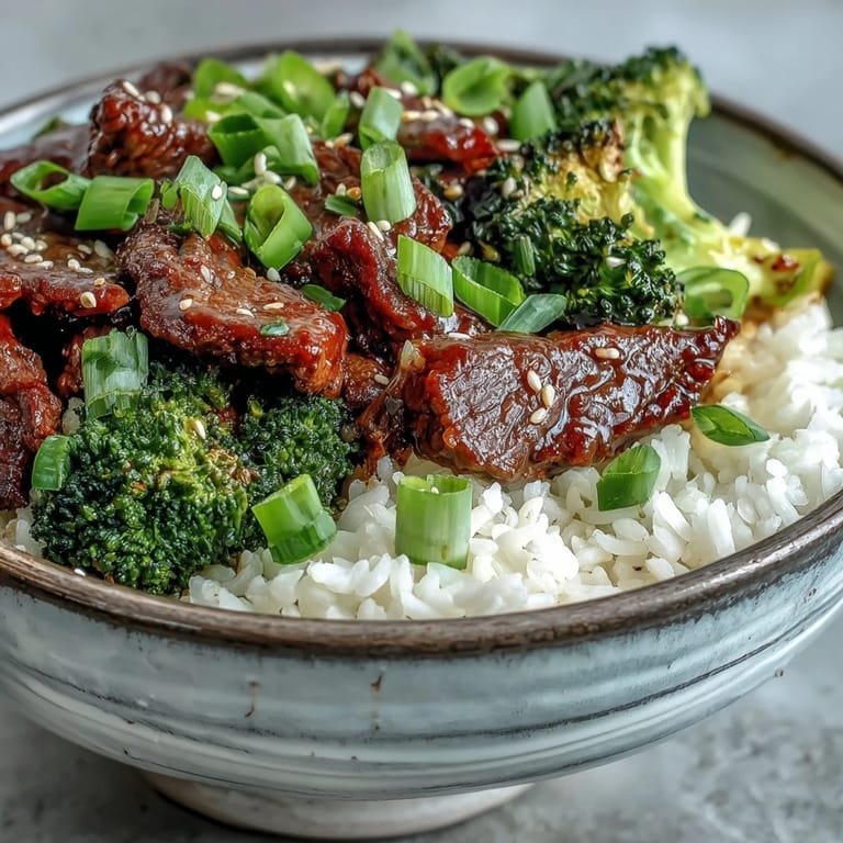 A close-up of juicy beef coated in glossy sauce atop fluffy rice, making a satisfying Beef and Broccoli Bowl dinner.